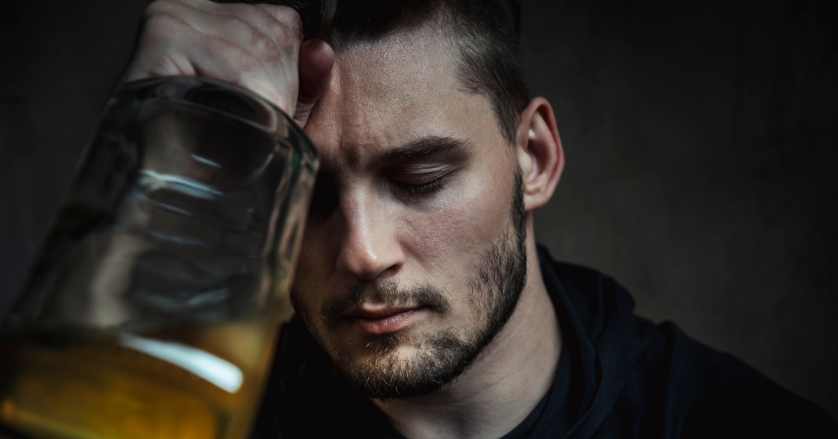 Man with closed eyes tightly holds onto a bottle of alcohol