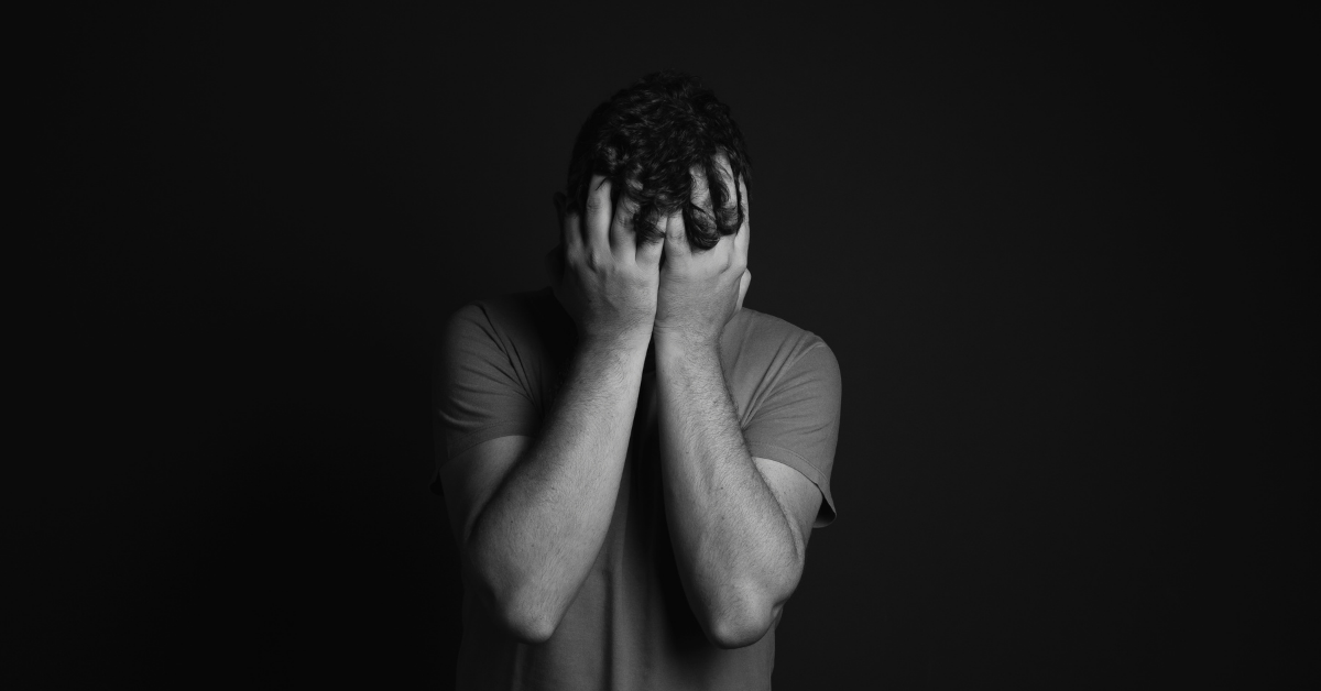 Black and white image of man holding his face in his hands