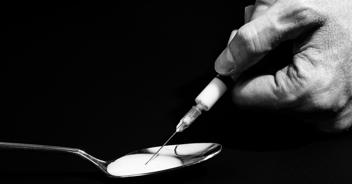A syringe absorbs liquid heroin from a spoon