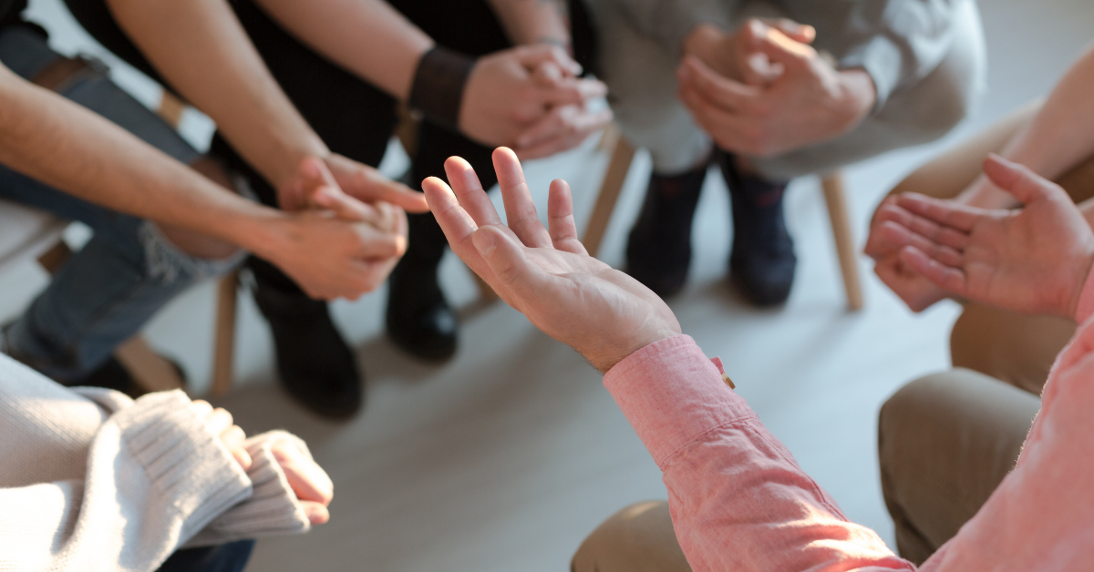 People sitting in a circle and clasping their own two hands together