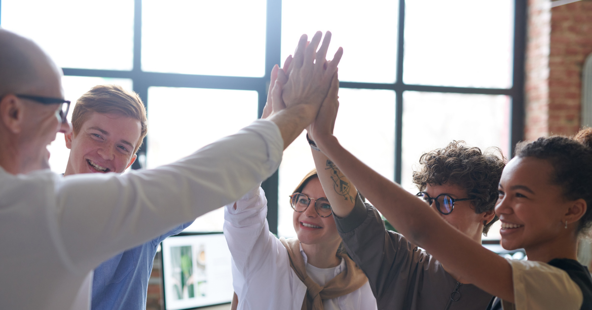 A group of smiling people all joining hands in the middle