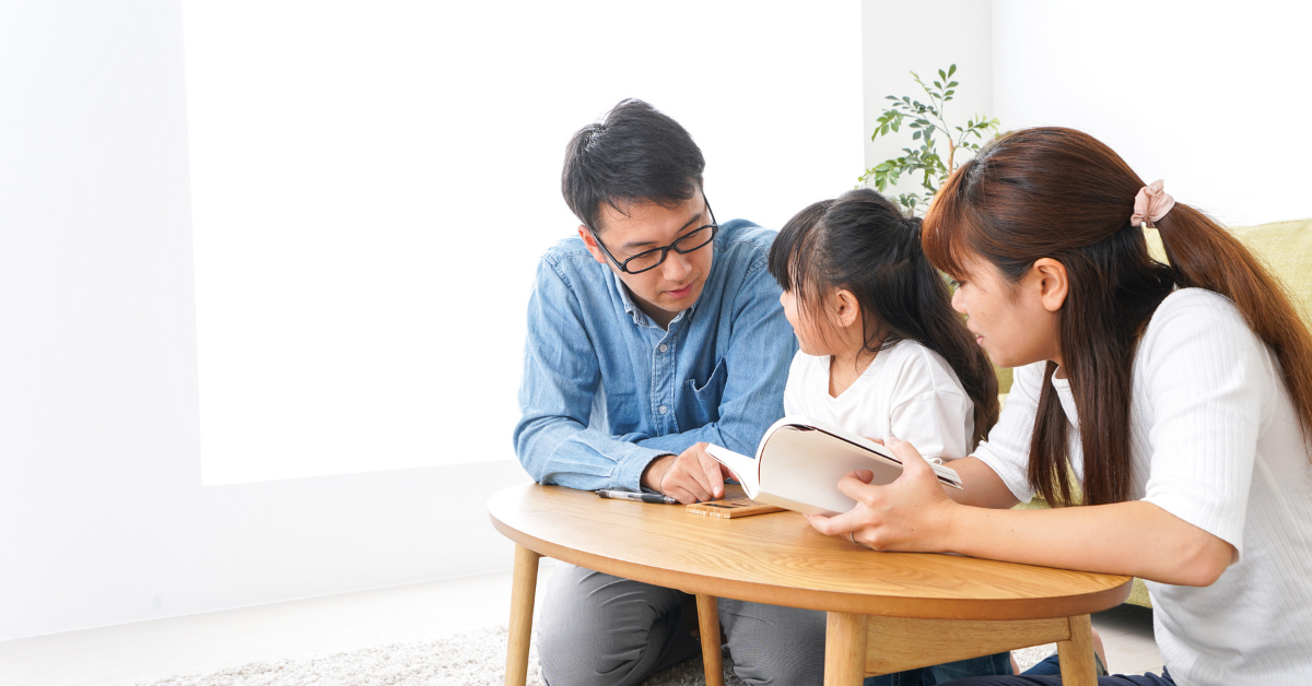 A mother and father Sitting with their daughter and learning with her