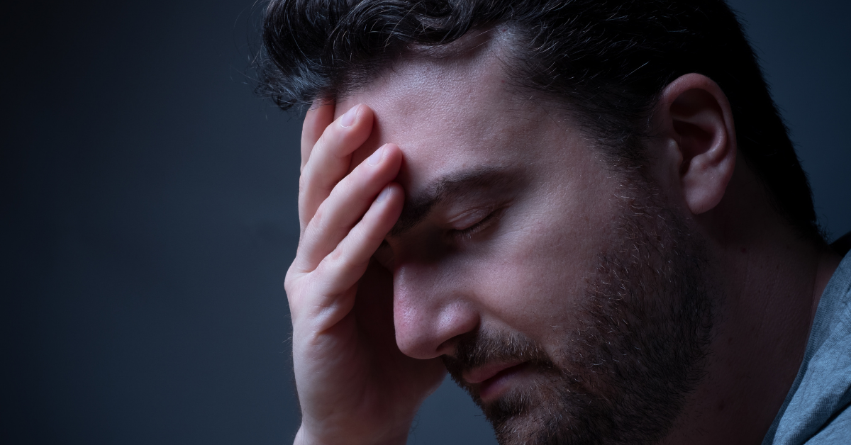 man with a beard holding his head in his hand